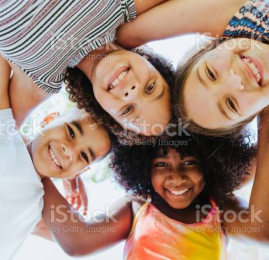 4 kids with heads together smiling looking down at the camera